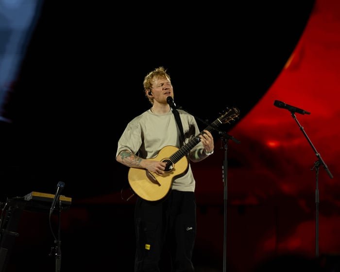 A single lone microphone stand on an enormous empty stadium stage, a 'For Lease' style landlord's clipboard resting against it, house lights on, no text.