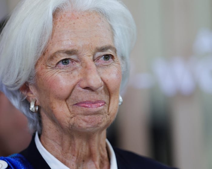 A lone central banker in a suit, standing at a podium with tape over her mouth, cheerfully peeling it off.