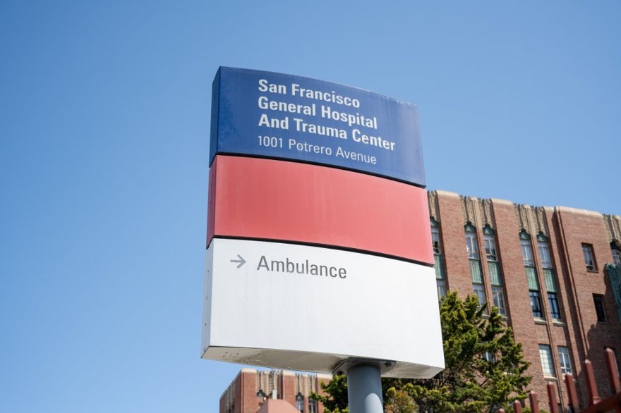 A lone hospital invoice growing into a giant paper monster towering over a tiny ambulance.